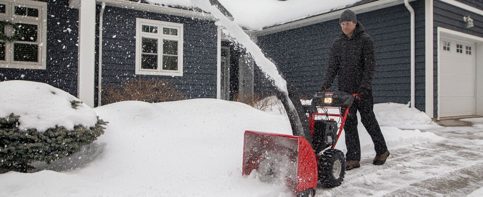 man clearing walkway with snow blower